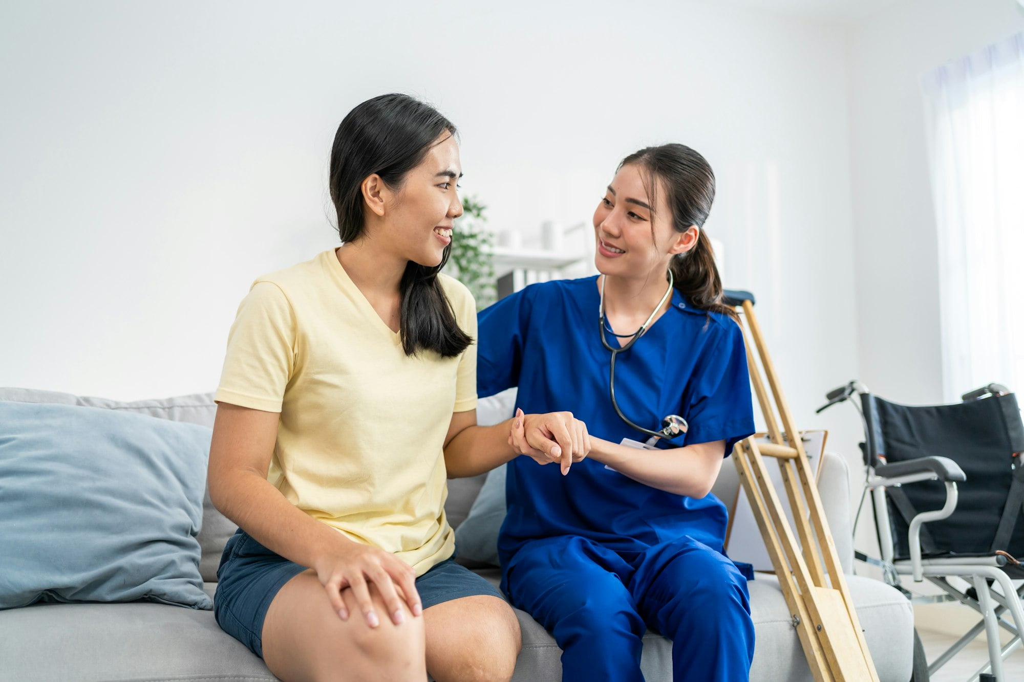 Asian female leg amputee doing physiotherapy with support from nurse.