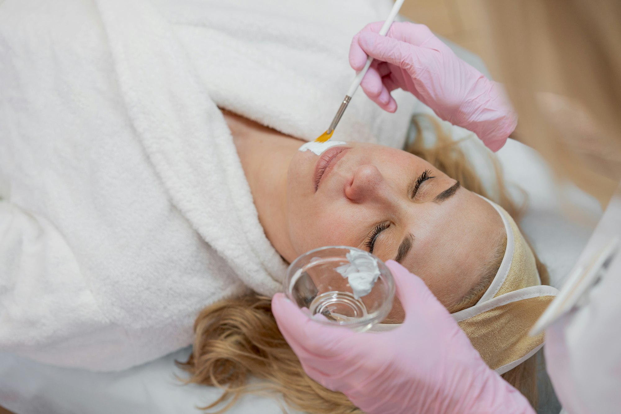 Female cosmetologist makes facial procedures for client clinic in aesthetic