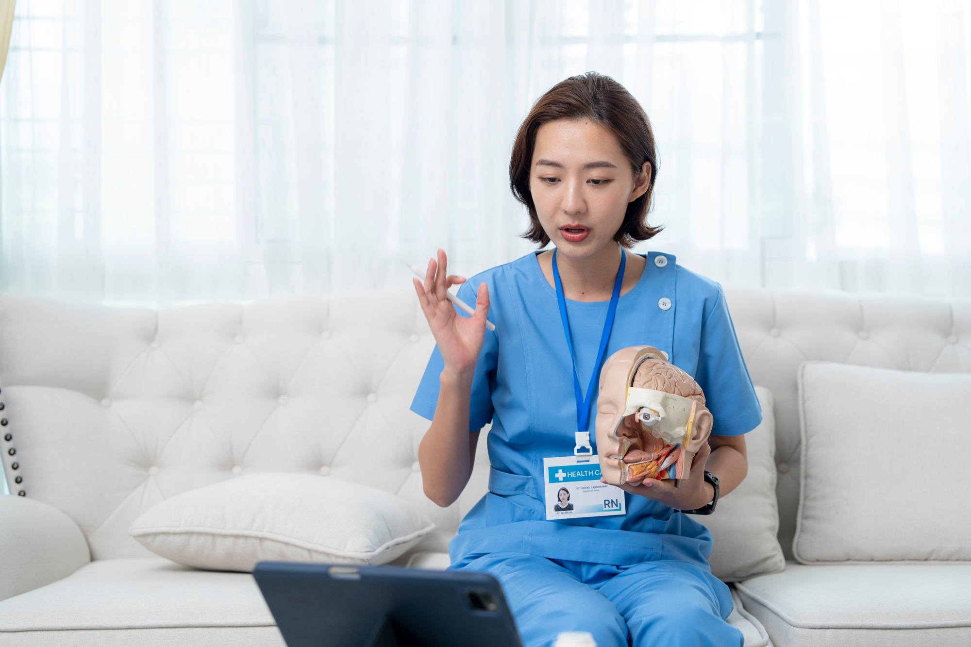 A medical professional in blue scrubs conducts an online lesson,